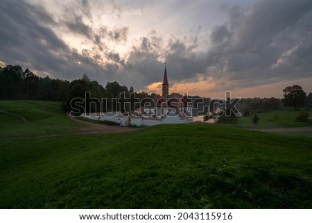 View of the Priory Palace on the shore of the Black Lake against the background of the sunset sky on an autumn evening, Gatchina, St. Petersburg, Russia
