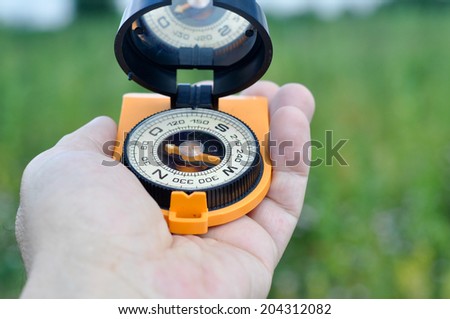 The compass in his hand. Magnetic compass in hand on the green meadows.