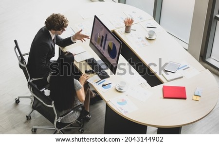 High view of caucasian marketing professional couple sit together at office desk with paper of creative idea and computer screen to discuss business account and portfolio chart to design work strategy Royalty-Free Stock Photo #2043144902