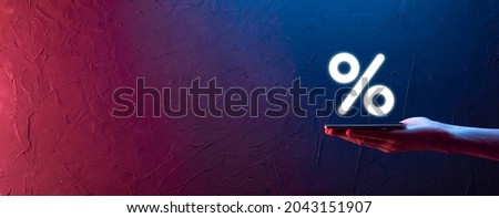 Male hand holding interest rate percent icon on blue background. Interest rate financial and mortgage rates concept.Banner with copy space. Royalty-Free Stock Photo #2043151907