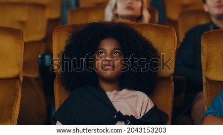 Attractive cheerful young black african girl laughing while watching film in movie theater. Lifestyle entertainment concept.