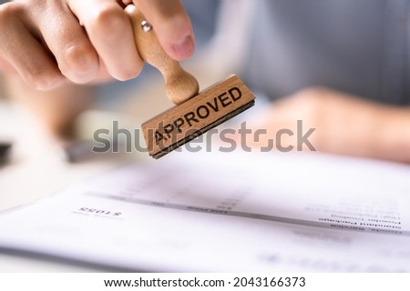 Hand Stamping With Approved Stamp On Document At Desk Royalty-Free Stock Photo #2043166373