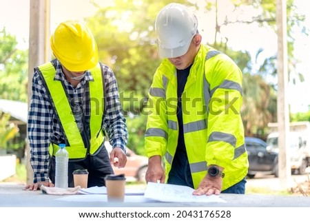 Construction worker, foreman stands and consults the construction plan with the construction site supervisor. Construction Workers talking in coffee break in site.