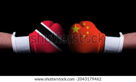 Two hands of wearing boxing gloves with China and Trinidad and Tobago flag. Boxing competition concept. Confrontation between two countries