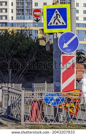 Stationary and portable road signs at a city intersection on an autumn sunny day