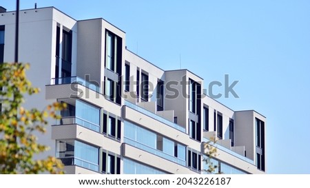 Ecological housing architecture. A modern residential building in the vicinity of trees. Ecology and green living in city, urban environment concept. Modern apartment building and green trees. Royalty-Free Stock Photo #2043226187