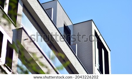 Ecological housing architecture. A modern residential building in the vicinity of trees. Ecology and green living in city, urban environment concept. Modern apartment building and green trees. Royalty-Free Stock Photo #2043226202