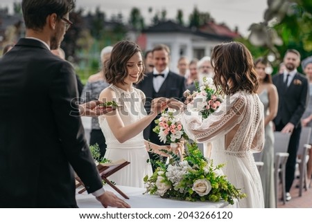 CU View of two LGBT females lesbians brides exchanging rings during wedding ceremony Royalty-Free Stock Photo #2043266120