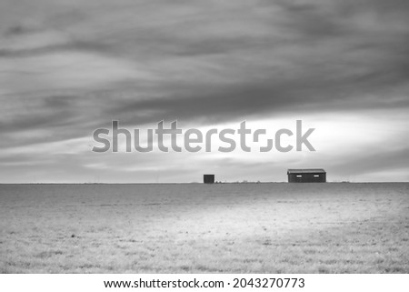 black and white landscape photograph of an isolated farm in the middle of a field in front of a cloudy sky at sunset (Wallonia, Villers-la-ville, Belgium)