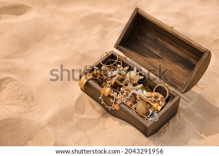 Open wooden chest with treasures on sand, space for text