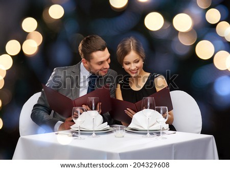 restaurant, couple and holiday concept - smiling couple with menus at restaurant Royalty-Free Stock Photo #204329608