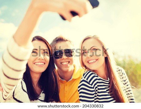 summer, holidays, technology, vacation and happiness concept - group of friends taking selfie with smartphone camera