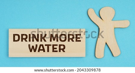 Medicine concept. On a blue background, a wooden figure of a man and a plate with the inscription - Drink More Water
