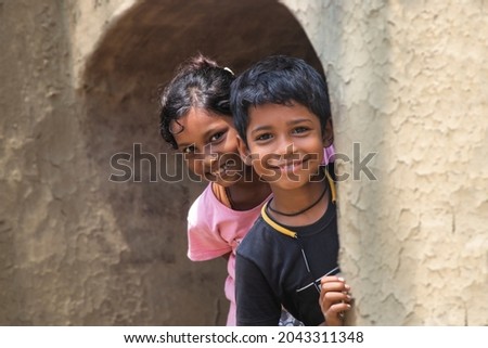 Indian rural Kids Peeking from Earthen wall Royalty-Free Stock Photo #2043311348