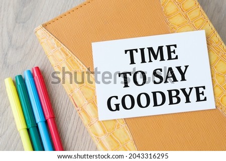 Time to say goodbye written on a white card that lies on a notebook