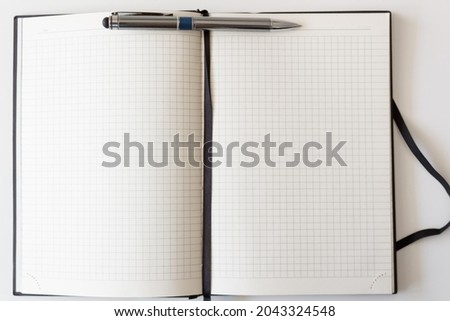 The concept of a workplace with an open notebook and a metal pen with a blue insert on a modern white table. Minimalism. Top view with a place to copy.