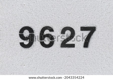 Black Number 9627 on the white wall. Spray paint. Number nine thousand six hundred and twenty seven.