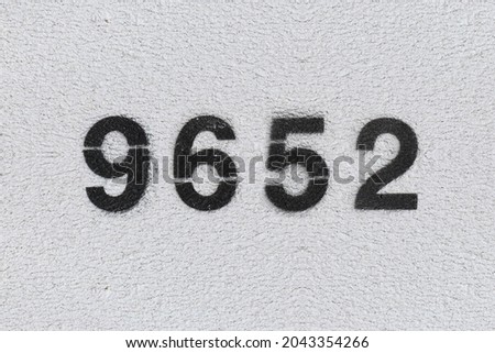 Black Number 9652 on the white wall. Spray paint. Number nine thousand six hundred fifty two.