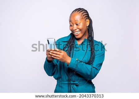 Happy excited lady using mobile phone at studio standing behind a white background Royalty-Free Stock Photo #2043370313