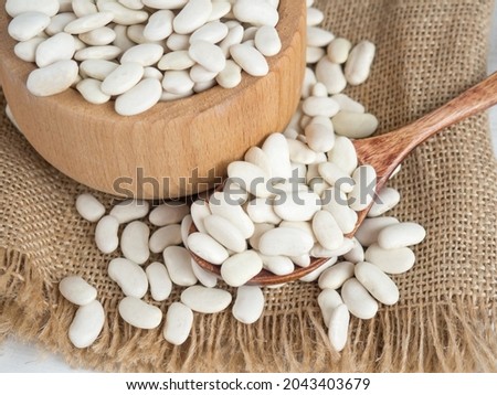 white beans in a wooden spoon on a white wooden table, copy space Royalty-Free Stock Photo #2043403679