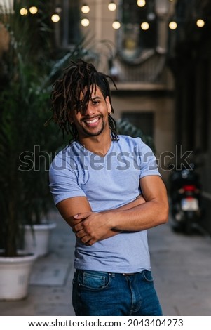 vertical portrait of an hispanic young man with dreadlocks. He is looking at camera and smiles Royalty-Free Stock Photo #2043404273