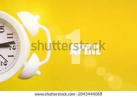 April 1st . Day 1 of month, Calendar date. White alarm clock on yellow background with calendar day. Spring month, day of the year concept Royalty-Free Stock Photo #2043444068