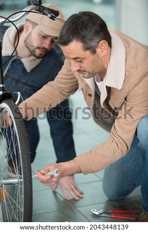 father and son repairing a bicycle in a garage