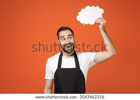 Young fun man barista bartender barman employee in apron white t-shirt work in coffee shop empty blank Say cloud speech bubble promotional content isolated on orange background Small business startup