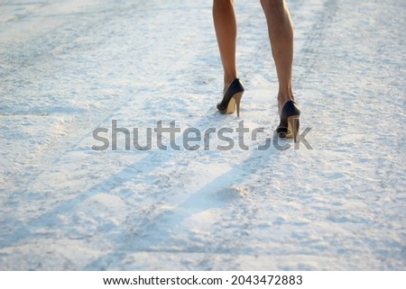 cropped photo of female legs in shoes on snow. selective focus.