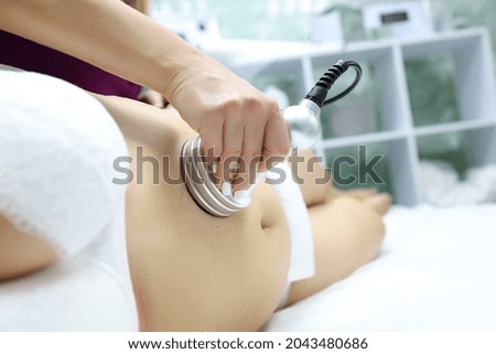 a model in a white bra and white panties is lying on the procedure with a massage master, he gives her an ultrasound massage, thus breaking up cellulite