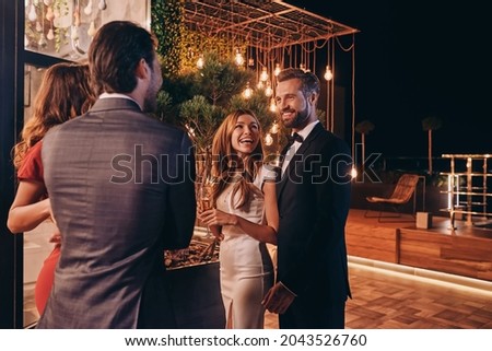 Group of people in formalwear communicating and smiling while spending time on luxury party Royalty-Free Stock Photo #2043526760