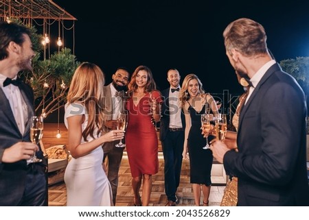 Group of beautiful people in formalwear communicating and smiling while spending time on luxury party Royalty-Free Stock Photo #2043526829