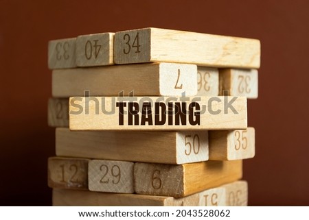 Wooden blocks with letters on a white table. The word is TRADING.