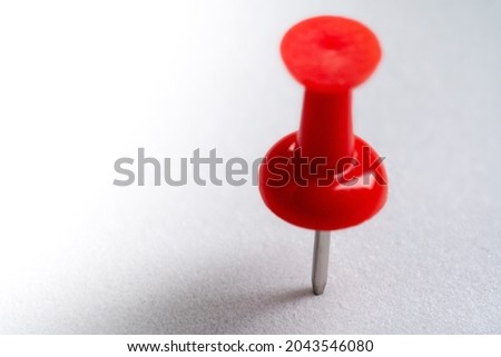 red push pin stuck in white floor. Macro thumbtack top view. white background and copy space Royalty-Free Stock Photo #2043546080