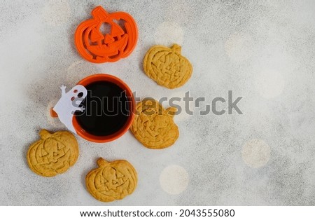 Breakfast or morning for halloween holiday, homemade pumpkin shaped cookies and bakeware cutting dish with a cup of coffee on concrete background