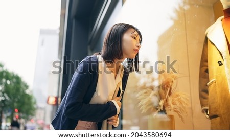 Young asian woman enjoying window shopping. Royalty-Free Stock Photo #2043580694