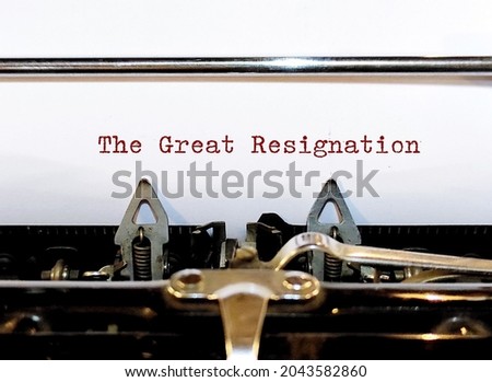 Old classic vintage typewriter with typed text THE GREAT RESIGNATION, a mass voluntary exodus from the workforce - millions workers are quitting their jobs. Royalty-Free Stock Photo #2043582860