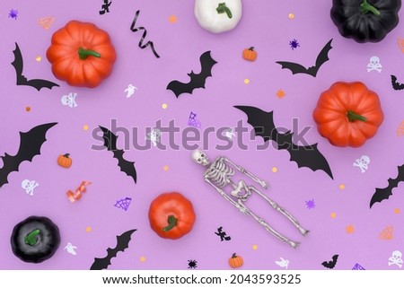 Happy Halloween concept. Halloween background made of multicolored decorative pumpkins, bats and skeleton. Decorated with pinata confetti in the shape of skulls, spiders, spider webs, bats and ghosts.