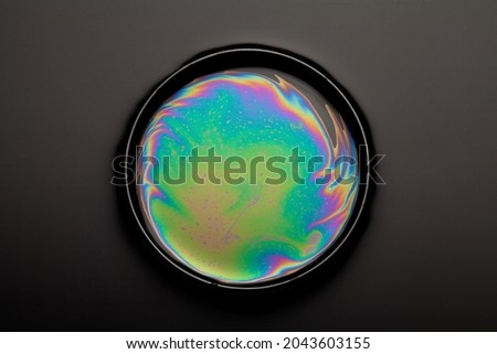 iridescent oil in dish on black background.