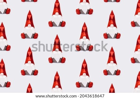 Volumetric paper Christmas gnomes in red pointed hat on light background, polygonal figure dwarf, Happy New Year and Merry Christmas holiday pattern.