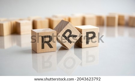 RRP - Recommended Retail Price acronym concept on cubes, gray background. Reflection on the mirrored surface of the table. Selective focus.