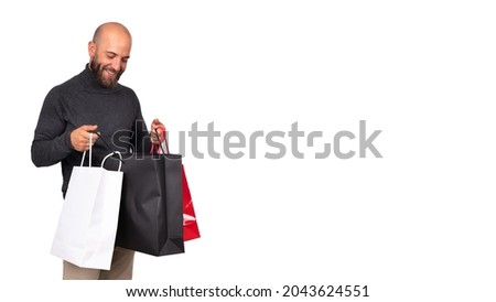 Young caucasian man looks inside shopping bag with satisfaction on white background. Horizontal banner. Copy space.
