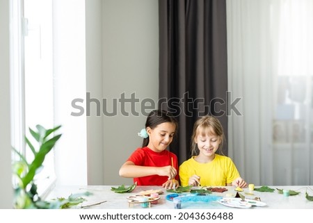 Child painting autumn leaves at home
