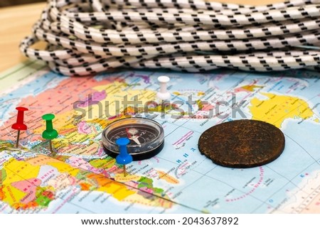 a compass a climbing rope and an old copper coin on the geographical map the buttons mark the places the concept of treasure hunting treasure hunting. High quality photo