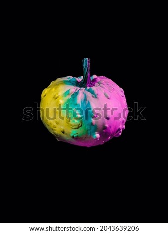 Fluorescent iridescent pumpkin isolated on a dark black background. Creative Halloween party or Thanksgiving concept. Fall season vegetable. Trendy vaporwave creative gradient.