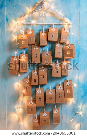 Creative Christmas Advent Calendar made of clip, string and cardboard on blue wooden background