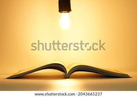 Open book under light bulb illuminate in darkness with empty blank space for design education background Royalty-Free Stock Photo #2043665237