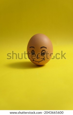 A chicken egg with a smiling face on a yellow background isolated and negative space