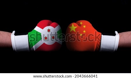 Two hands of wearing boxing gloves with China and Burundi flag. Boxing competition concept. Confrontation between two countries