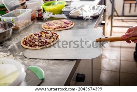 hand of chef baker making pizza at kitchen. Put on landing shovel and send it to the oven.